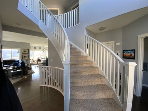 Modern white painted curved staircase banister SE Calgary